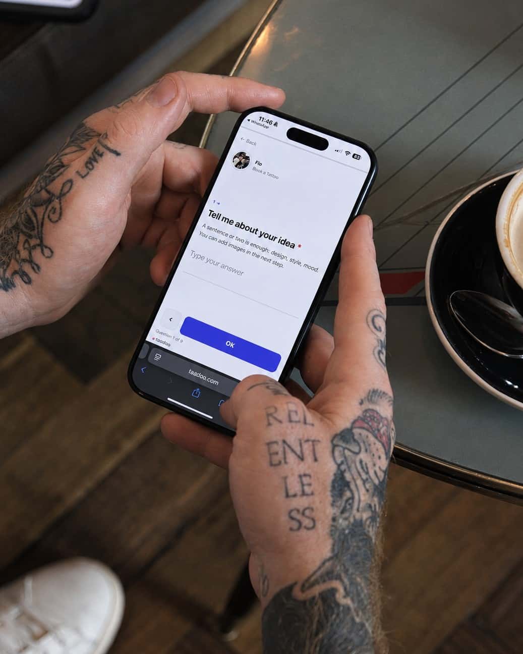 Tatuatore che compila il modulo di richiesta sul telefono in un caffè