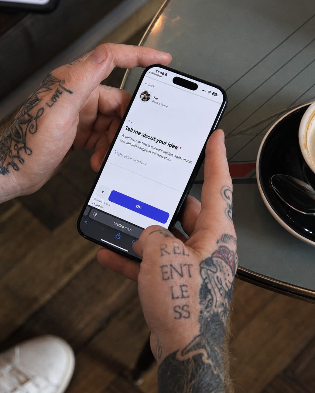 Tattoo artist filling in the request form on a phone in a café