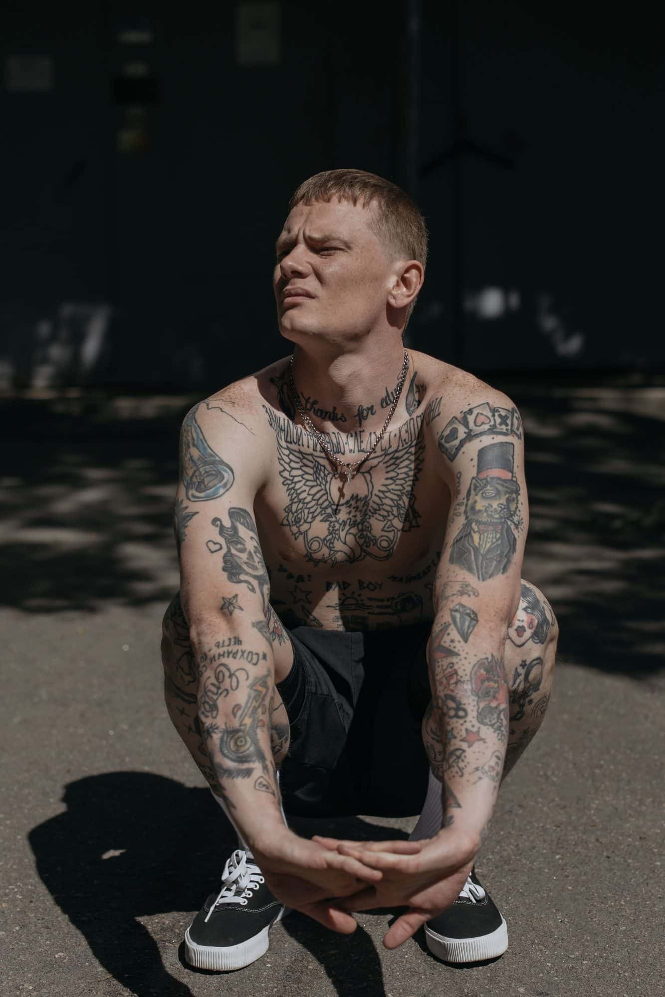 Uomo con tatuaggi flash su braccia e petto