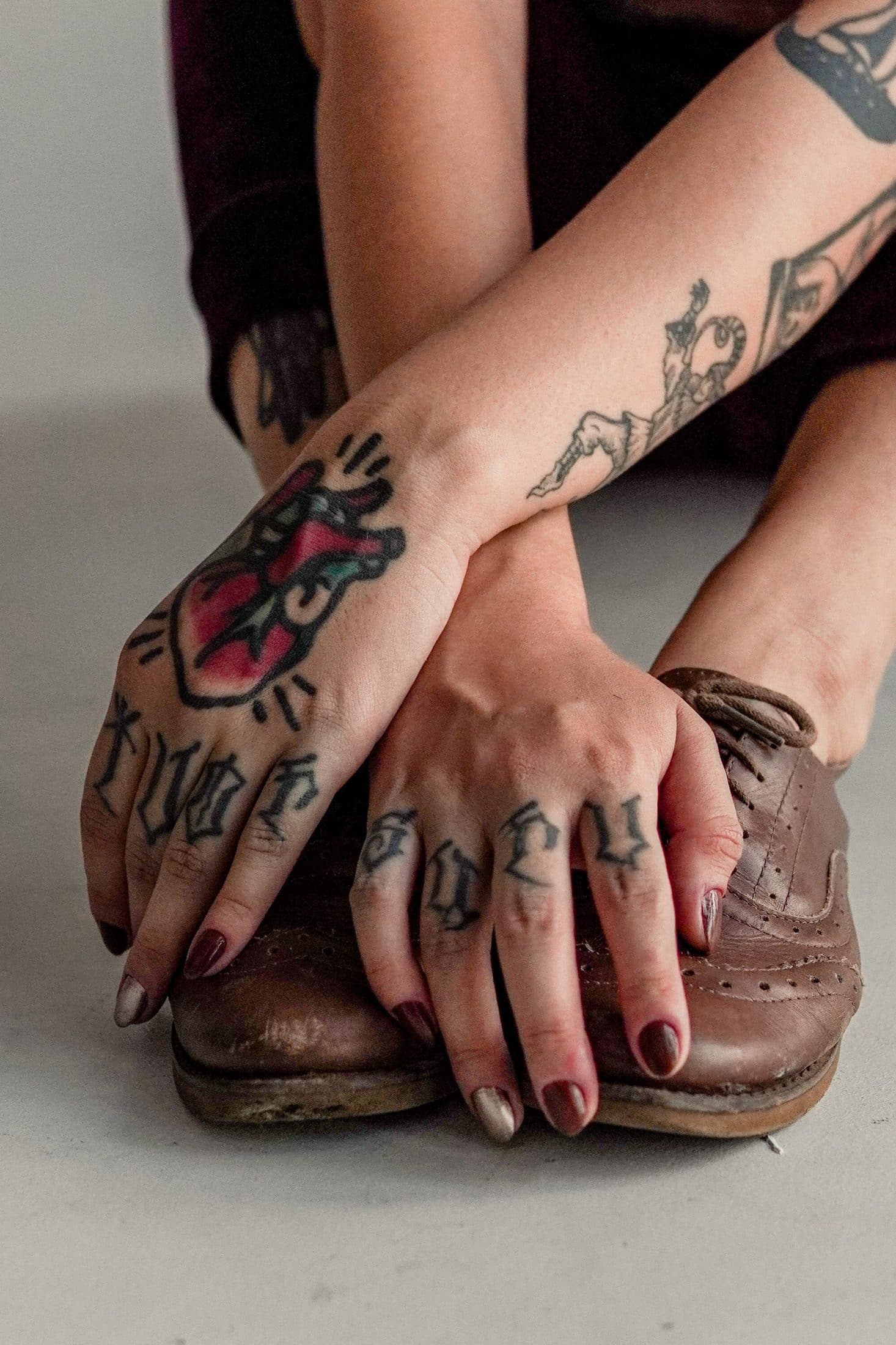 Tattooed hands resting on shoes