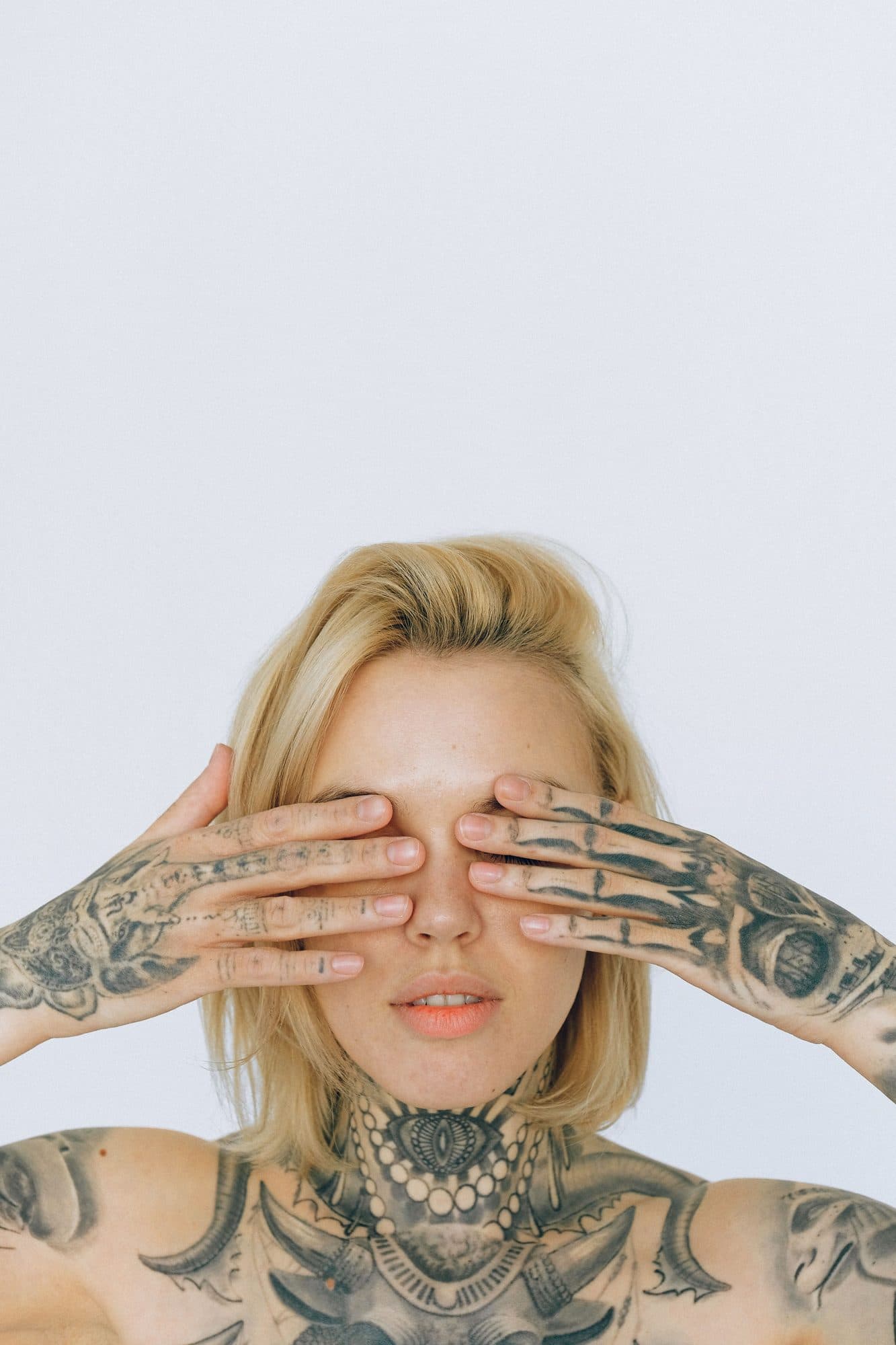 Tattooed woman looking through her fingers