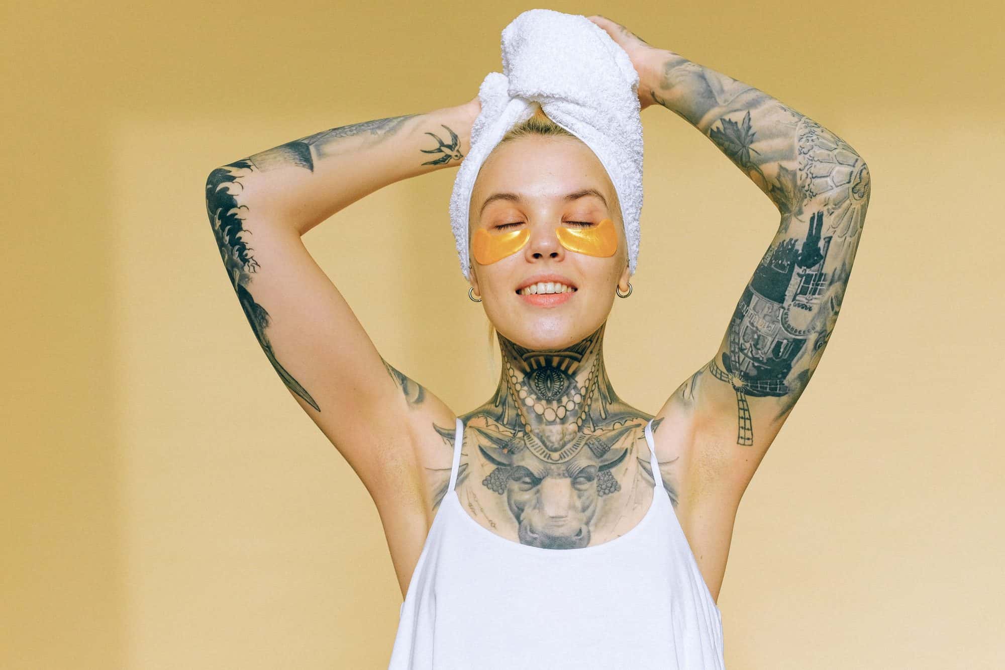 Donna tatuata con un asciugamano sui capelli che si rilassa
